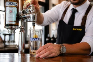 Barman versant une dose précise de Ricard de 2 cl avec un doseur optic chrome dans un bar français